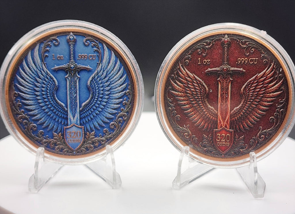 Two round fantasy-themed coin medallions with winged swords and shields, displayed on clear acrylic stands against a dark background. One medallion is blue with bronze-toned details, and the other is reddish-brown with bronze-toned details.